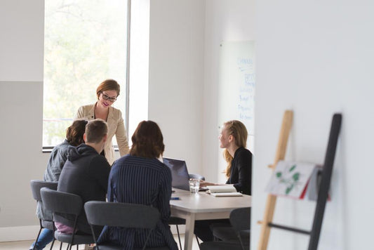A group of people in a conference room with a whiteboard in the background.